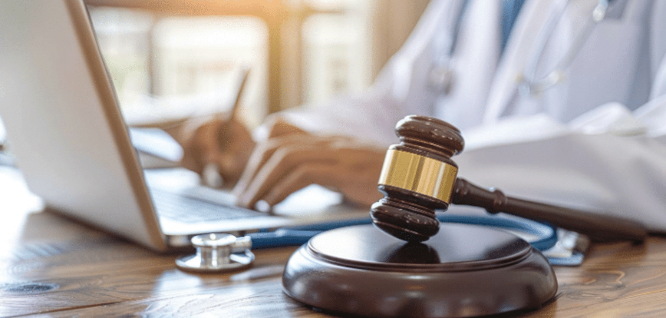 Gavel on a desk with a doctor working in the background