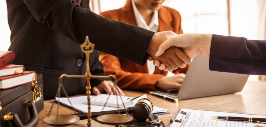 Shaking hands over a desk with legal documents