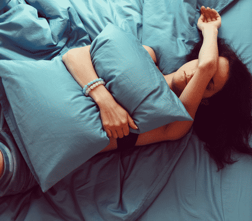 Woman clutching pillow on bed in pain