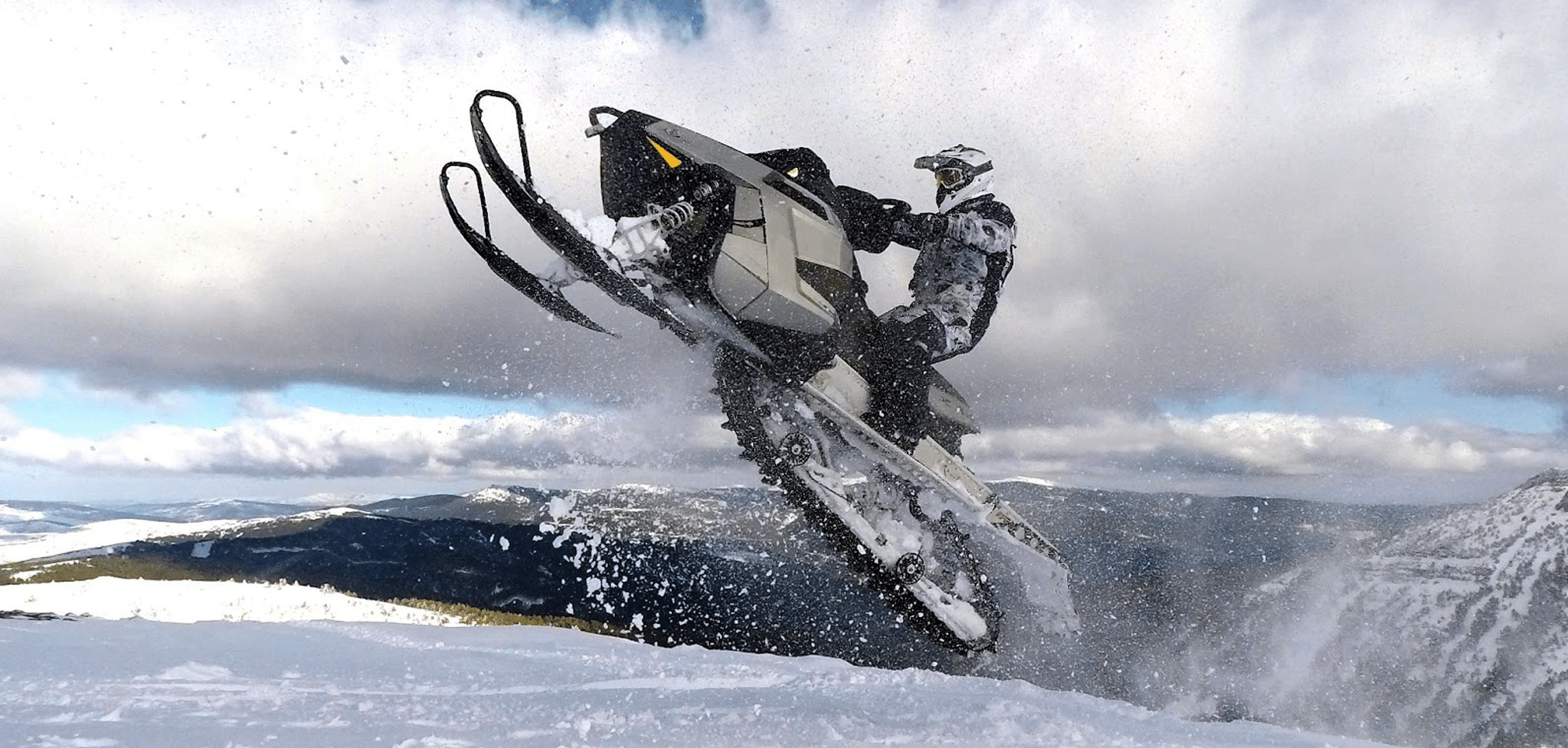 Rider jumping with snowmobile between clouds