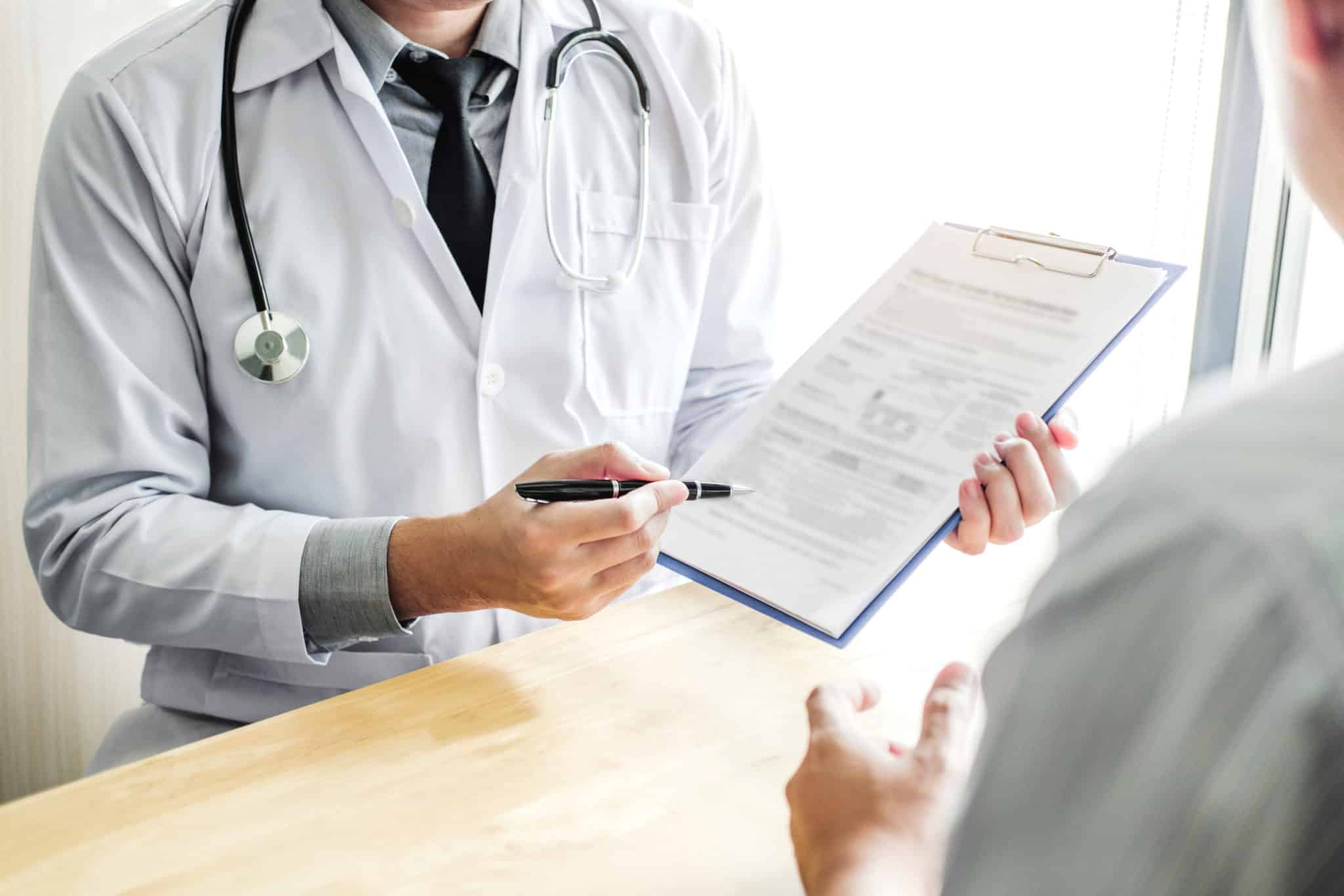 Doctor pointing to paperwork with pen to sign