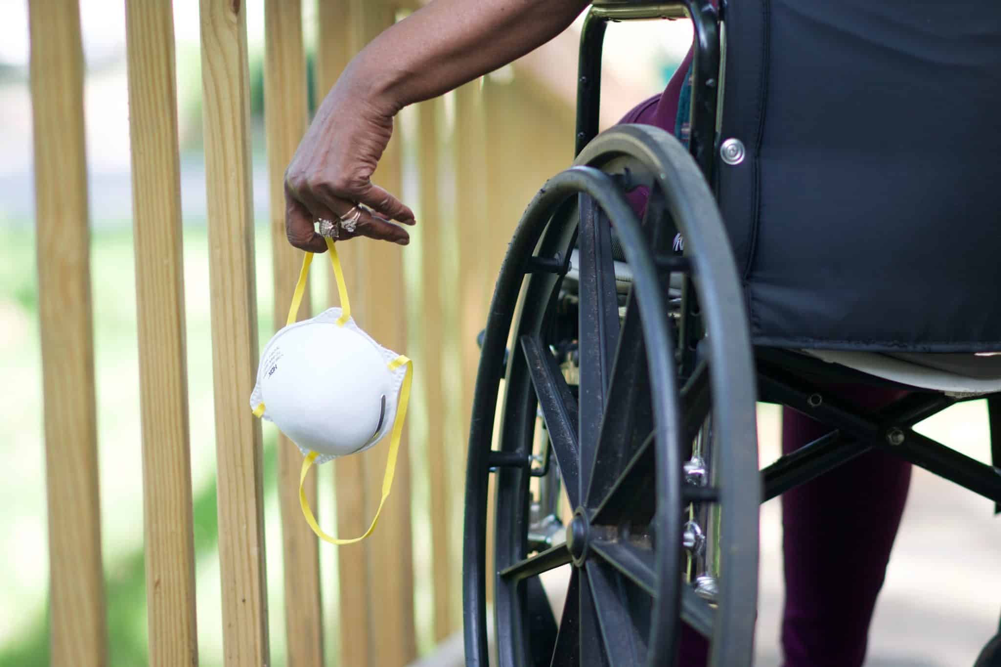 Person in wheelchair holding a mask