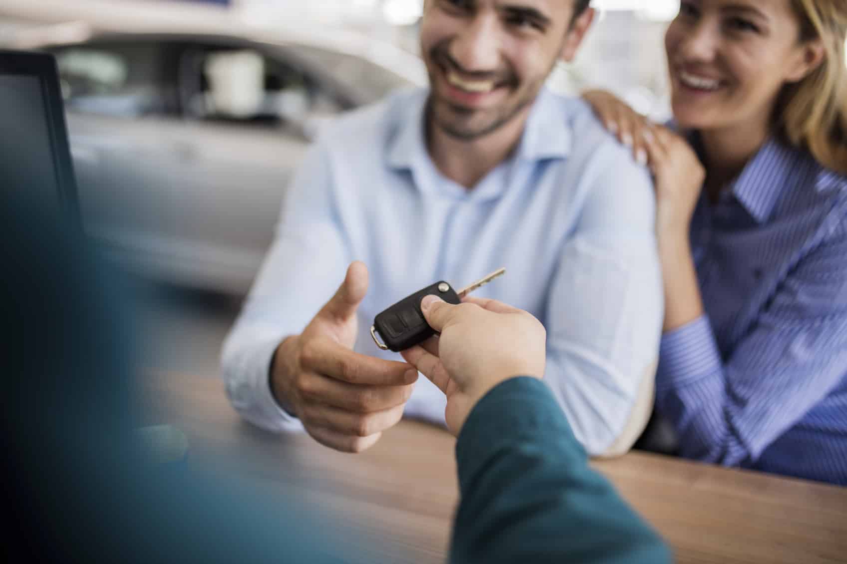 Close up of smiling couple receiving new car key.